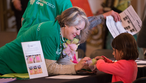 SFO volunteer helping child make a flower