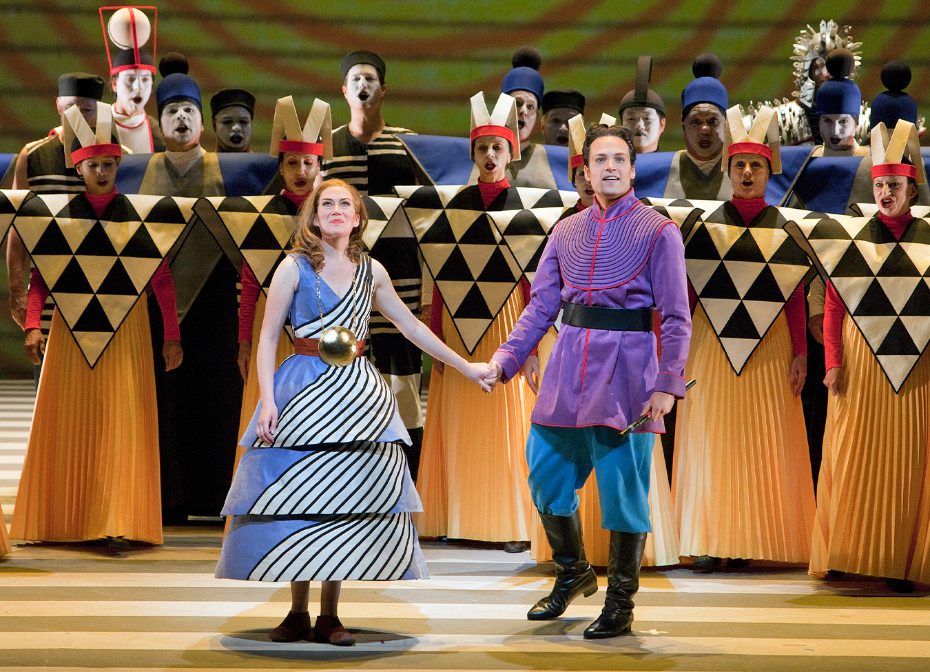 The Magic Flute's Pamina and Papageno holding hands with a group of singers behind them.