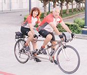 Chris Miller and Gary Glaser on a tandem bike wearing matching outfits.