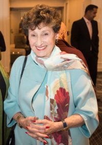 Ione Gille in a light blue coat with a white and red scarf.