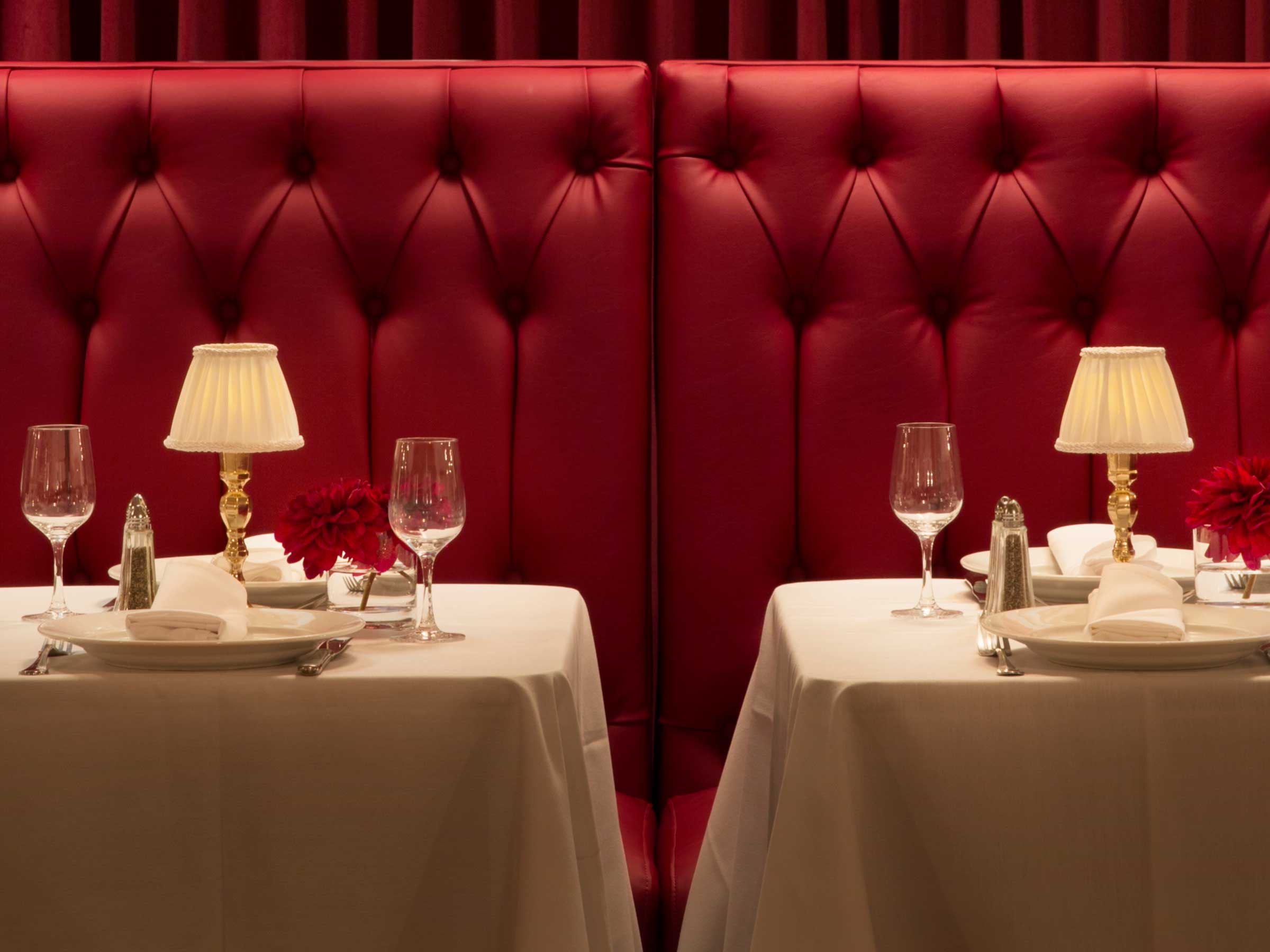 booth with two tables set for dinner