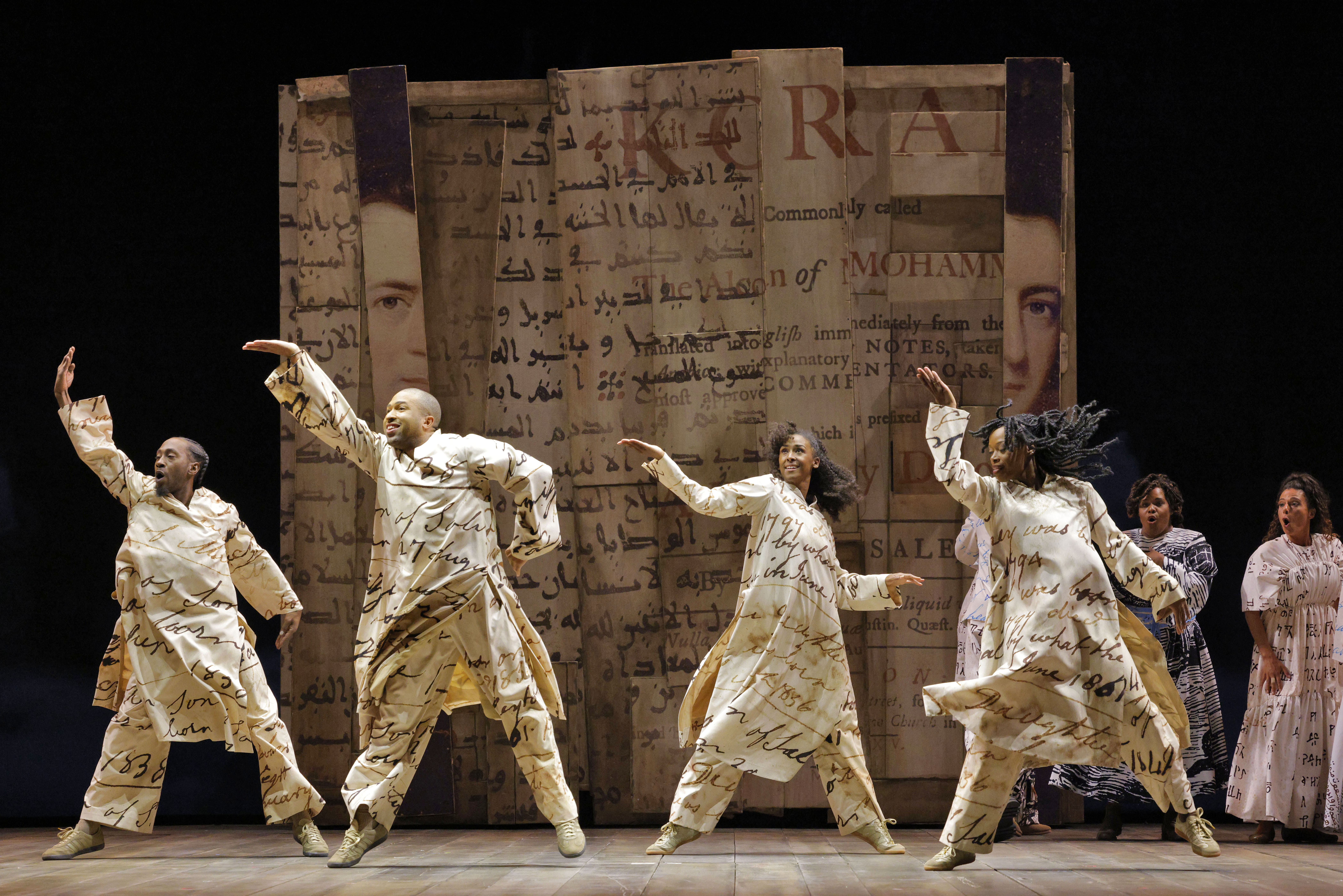 people dancing on stage wearing lettered clothing