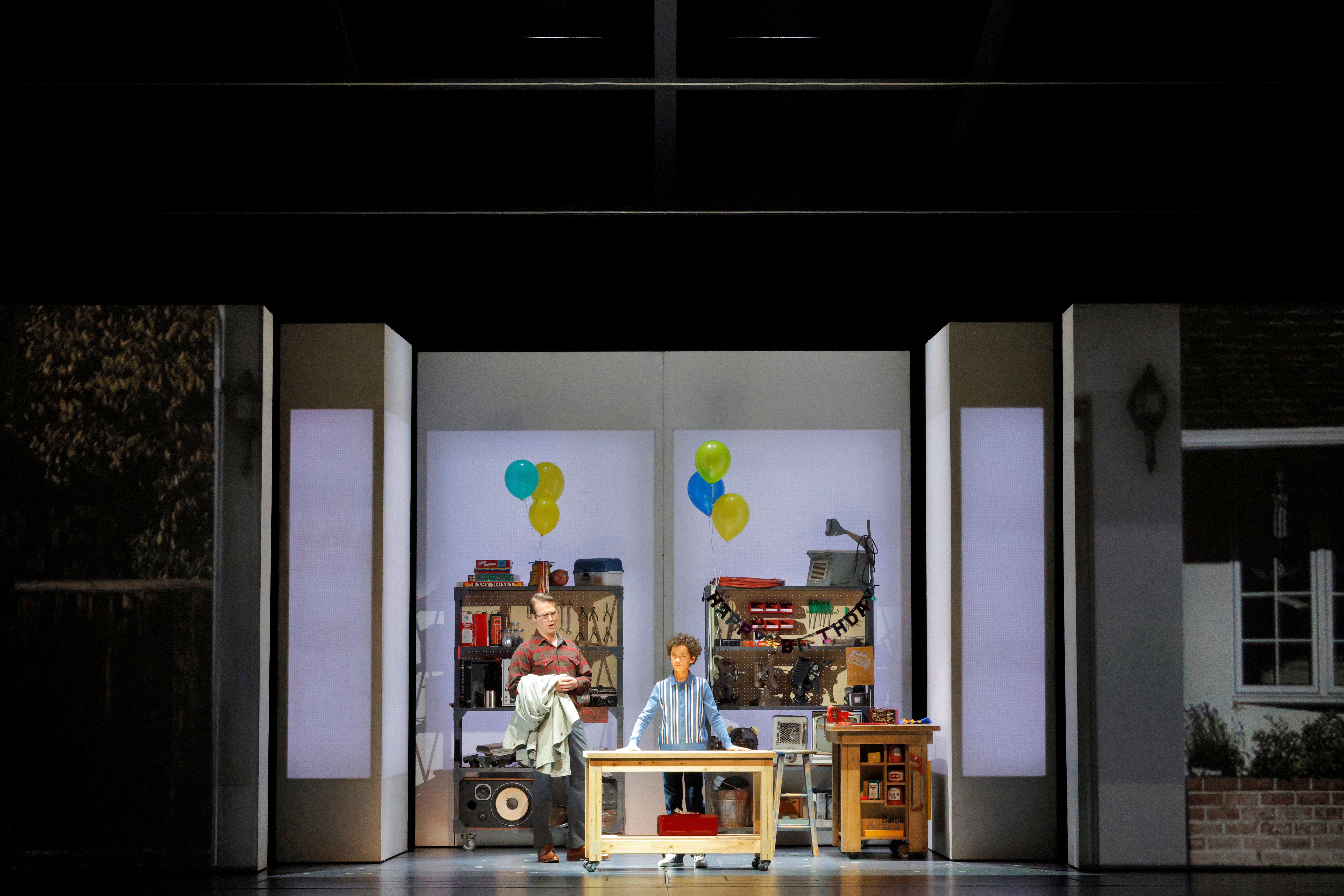 man and child on stage with a set that looks like a garage